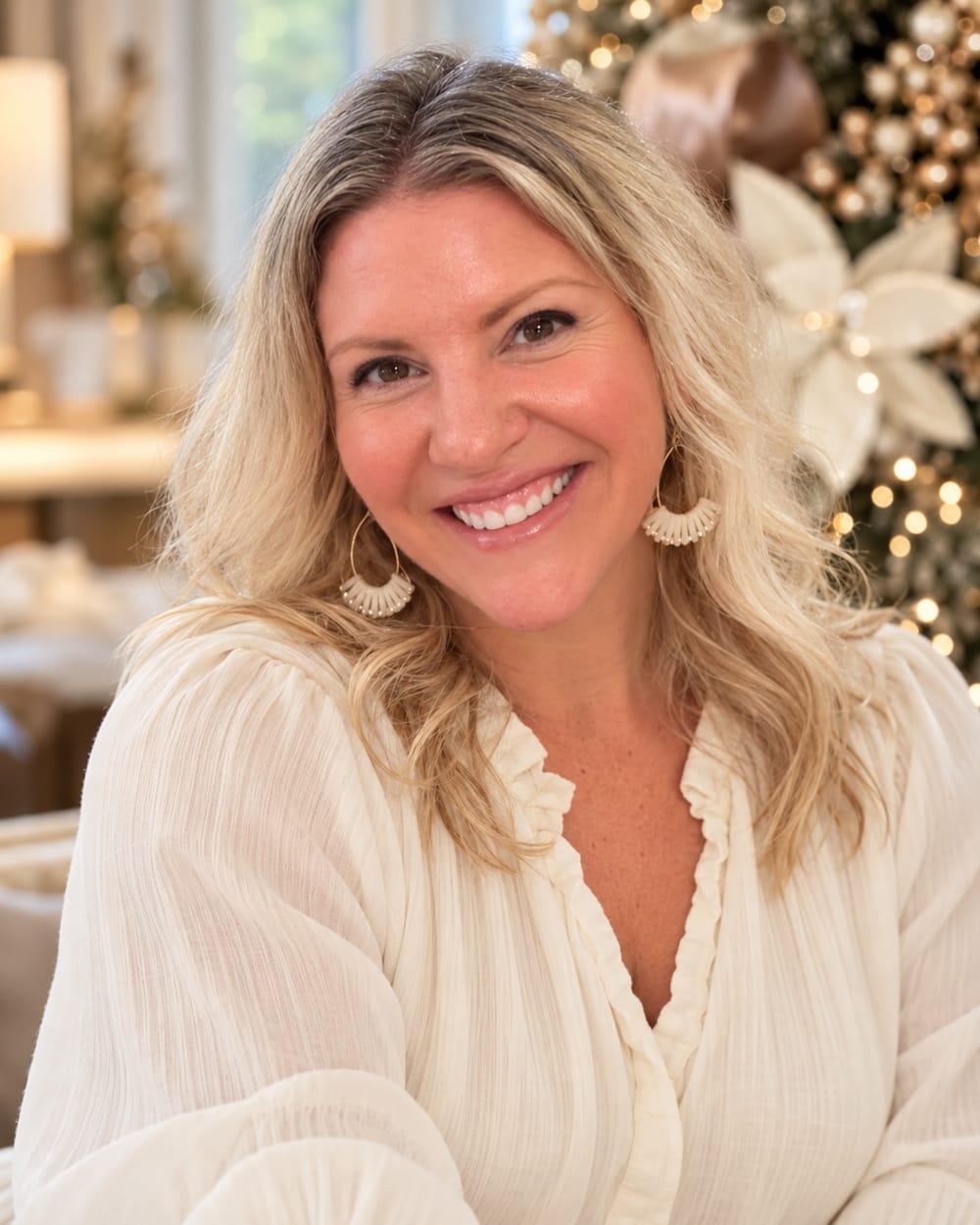Nadine Hill, smiling, in front of a champagne and ivory Christmas tree